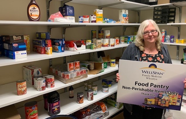 Licensed Practical Nurse and Health Coach Kim Richcreek poses by food pantry.